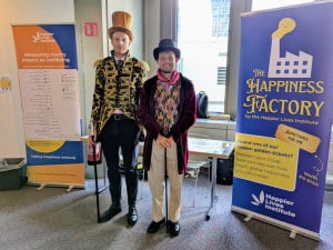 Michael Plant and Ben Stewart from the Happier Lives Institute at the Happiness Factory stand during the ISQOLS 2025 conference.