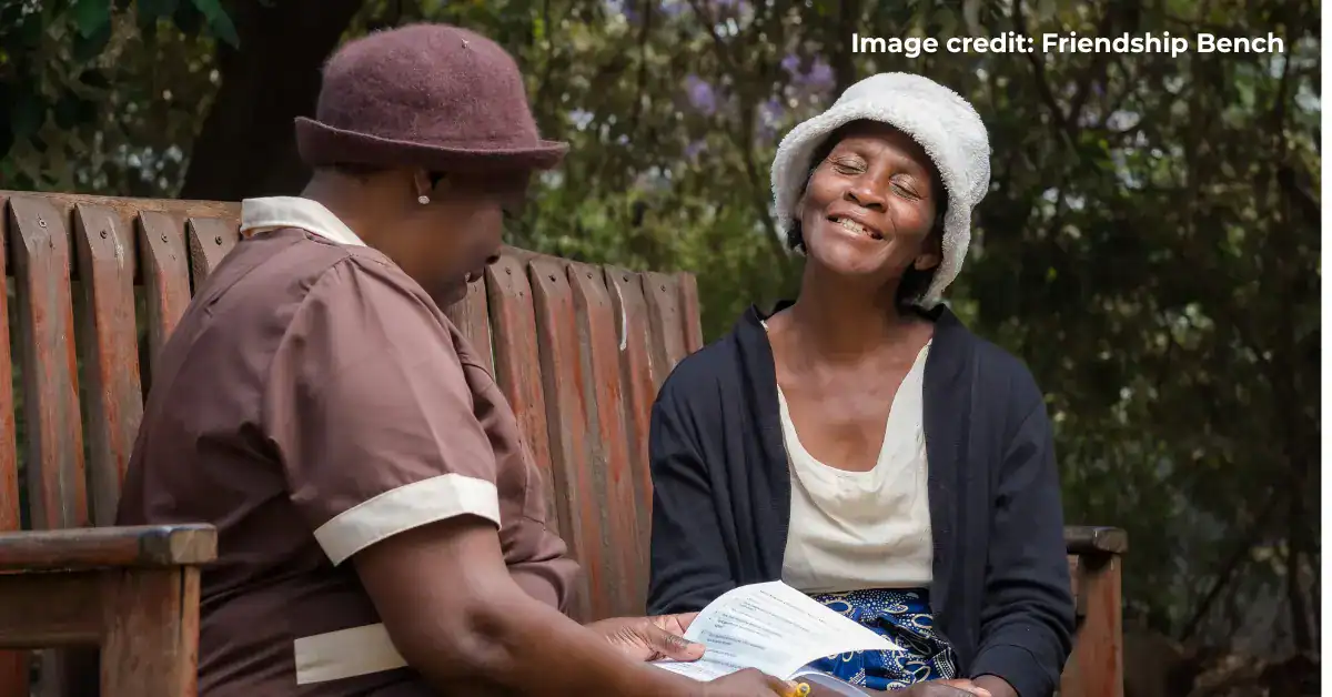 Two women sitting on a park bench, smiling and talking.