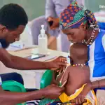 Healthcare worker administering treatment to a child in Nigeria.